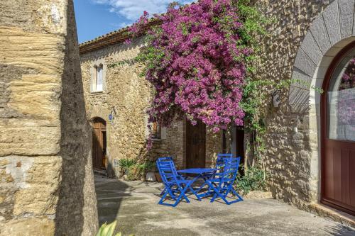 two blue chairs and a table in front of a building with purple flowers at Casa Blava in Orriols