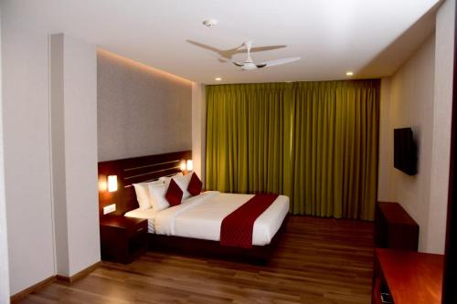 um quarto com uma cama e uma cortina verde em HOTEL EMERALD PALACE em Kottiyam