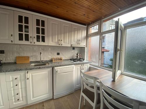 a kitchen with white cabinets and a table with chairs at REAL FAMILY APART new in Soğuksu