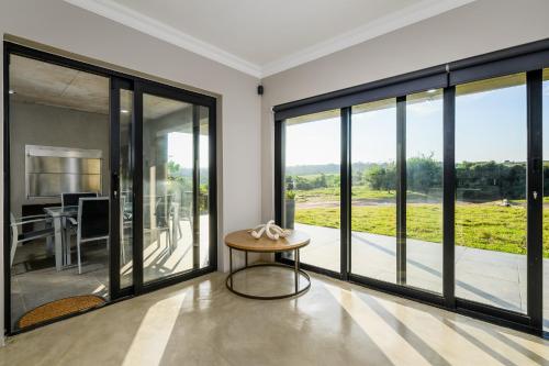 a living room with large windows and a table at Kragga Kamma Game Park in Port Elizabeth