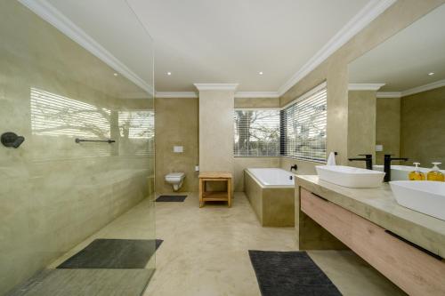 Un baño con dos lavabos, una bañera y una ducha. en Kragga Kamma Game Park, en Port Elizabeth