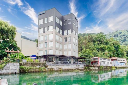 um edifício alto ao lado de um corpo de água em H& 日月潭水漾 l 伊達邵老街 l 湖景 em Yuchi