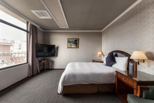 a hotel room with a bed and a large window at Hotel j-Metropolis in Hsinchu City