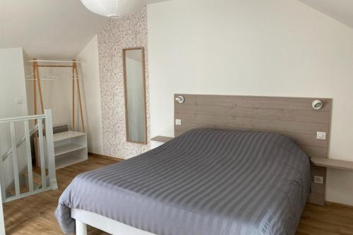een slaapkamer met een bed en een spiegel aan de muur bij Le Petit Cellier 