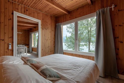 1 dormitorio con cama y ventana grande en Chalet Alessandrini - Private Lakeside Beach, en Tenna 