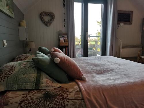 ein Schlafzimmer mit einem Bett mit Kissen und einem Fenster in der Unterkunft Entre monts et collines B&B et espace détente in Mont-de-l'Enclus
