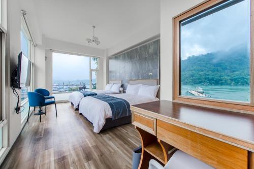 a bedroom with a bed and a desk and a large window at Sun Moon Lake Shui Yang Hall in Yuchi