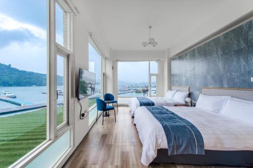 two beds in a room with a large window at Sun Moon Lake Shui Yang Hall in Yuchi