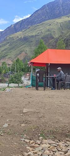 a man sitting at a table under a red tent at Buddy Hikers Stay Badrinath in Badrīnāth