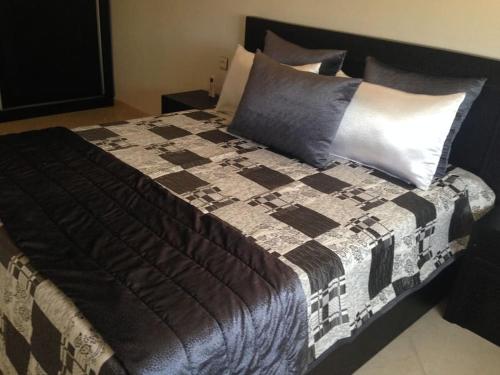 Oued Laou的住宿－APPARTEMENT TOUT CONFORT CLIMATISE，一张大床,配有黑色和白色的毯子和枕头