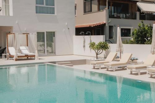 a swimming pool with lounge chairs and a building at Ennea suites-Space suite in Flámbouras