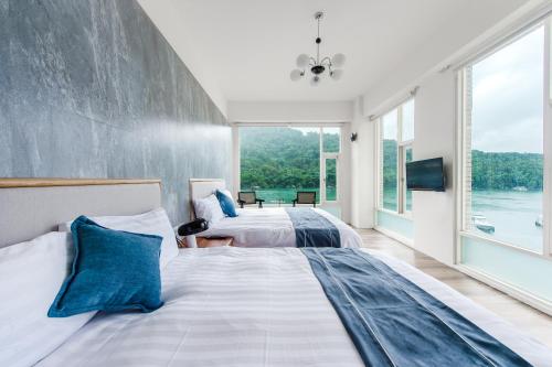 two beds in a room with large windows at Sun Moon Lake Shui Yang Hall in Yuchi