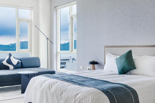 a bedroom with a bed and a couch and windows at Sun Moon Lake Shui Yang Hall in Yuchi