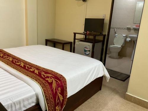 a bedroom with a bed and a bathroom with a toilet at Khách sạn Minh Châu - Hòa Hưng in Ho Chi Minh City