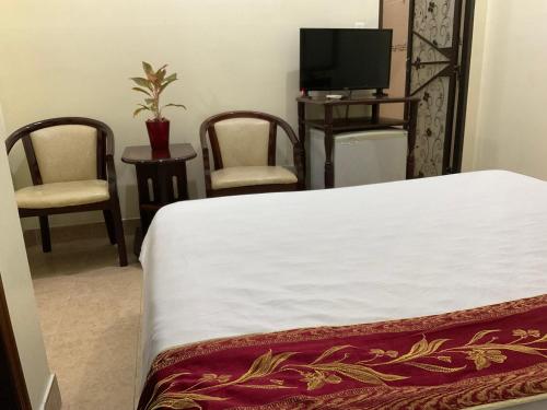 a bedroom with a bed and two chairs and a tv at Khách sạn Minh Châu - Hòa Hưng in Ho Chi Minh City