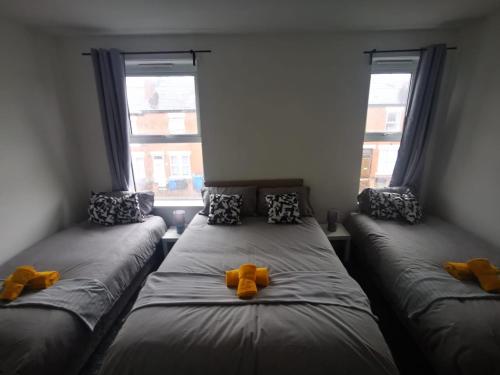 two twin beds in a room with two windows at Sutherland Place - Near Derby City Center in Derby