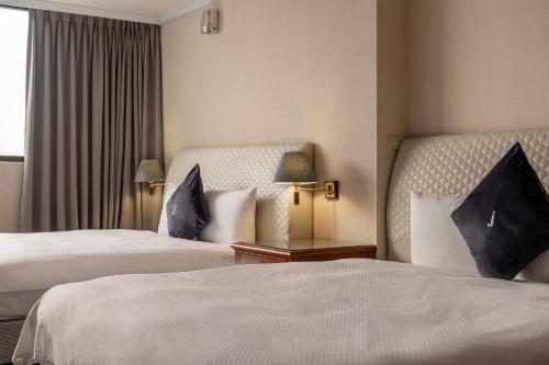 a hotel room with two beds and a window at Hotel j-Metropolis in Hsinchu City