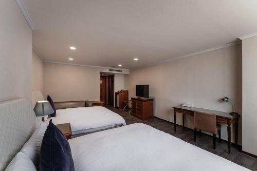 a hotel room with two beds and a desk at Hotel j-Metropolis in Hsinchu City