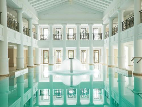 an indoor pool with a table in the middle of a building at Grecotel LUXME Palms at Riviera Olympia & Aqua Park in Loutra Killinis