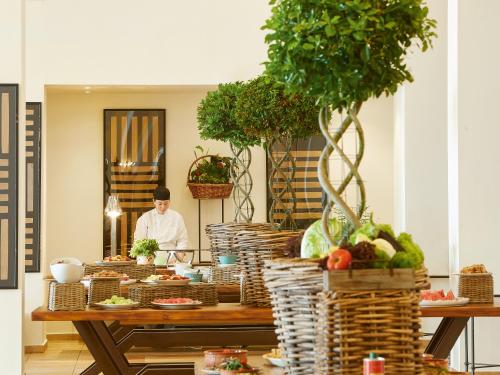 a chef standing behind a table with food on it at Grecotel LUXME Palms at Riviera Olympia & Aqua Park in Loutra Killinis