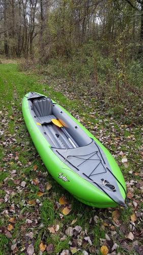 a green kayak sitting on the grass in the woods at Apartman Zeko in Veliki Lovrečan