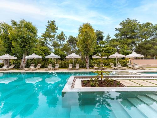 a swimming pool with chairs and umbrellas at Grecotel Ilia Palms & Aqua Park in Loutra Killinis