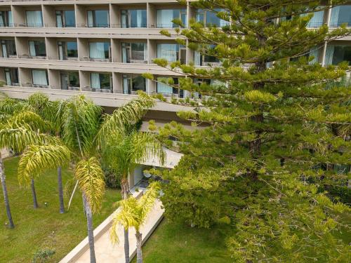 an apartment building with palm trees in front of it at Grecotel LUXME Palms at Riviera Olympia & Aqua Park in Loutra Killinis