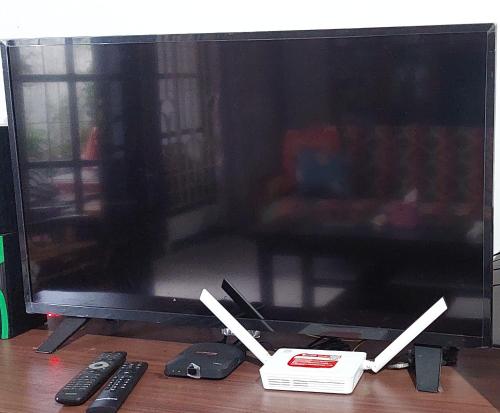 un écran de télévision avec deux commandes à distance sur une table dans l'établissement Homestay Ngaso Dalem, à Wonosobo