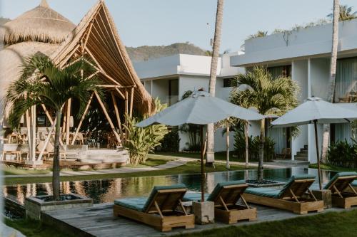 a resort with a swimming pool with chairs and umbrellas at Sikara Lombok Hotel in Kuta Lombok