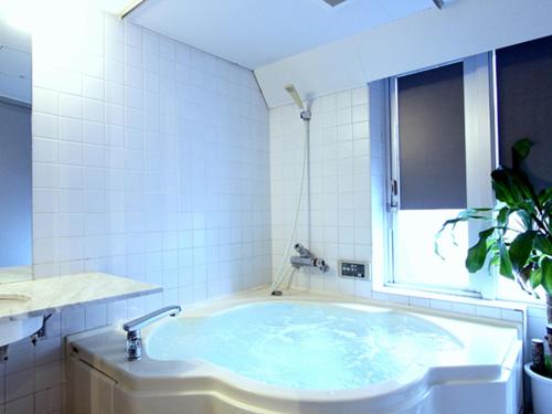 東京にあるホテルリブマックスBUDGET後楽園の白いタイル張りのバスルーム(バスタブ付)