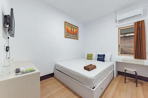 a small white bedroom with a bed and a window at Urbanview Hotel Tropical Ketapang by RedDoorz in Karawang