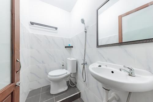 a bathroom with a sink and a toilet and a mirror at Urbanview Hotel Tropical Ketapang by RedDoorz in Karawang