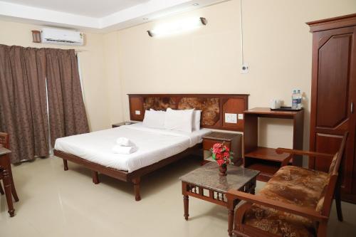 ein Hotelzimmer mit einem Bett und einem Tisch in der Unterkunft Pagoda Heritage Inn in Alappuzha