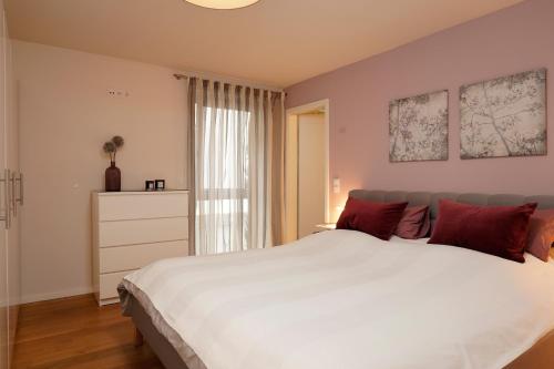 a bedroom with a large white bed with red pillows at Design Apartment in Eppelheim in Eppelheim