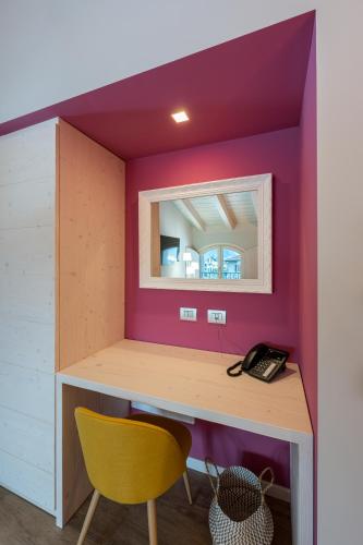 a room with a desk and a yellow chair at Bianco Hotel in Primaluna