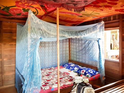a bedroom with a canopy bed in a house at Farmer home stay & trekking in Banlung