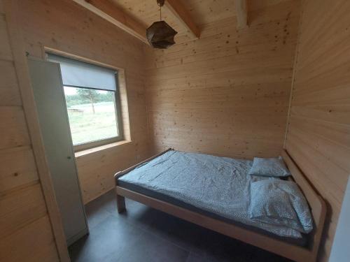 Łóżko w drewnianym pokoju z oknem w obiekcie Domek pod Chełmową Górą w Krasnobrodzie
