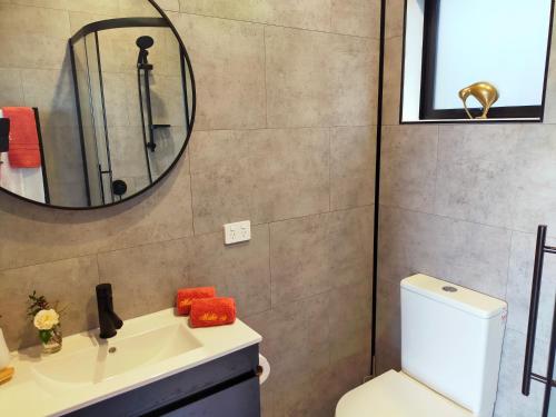 a bathroom with a sink and a mirror and a toilet at Secluded, private rural retreat mins from Warkworth -"Avondale" Minihouse in Warkworth