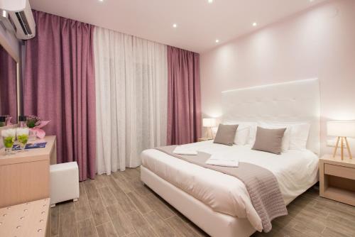 a bedroom with a large white bed with pink curtains at Angelica Hotel in Limenas