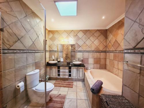 a bathroom with a tub and a toilet and a sink at Elements golf reserve in Bela-Bela