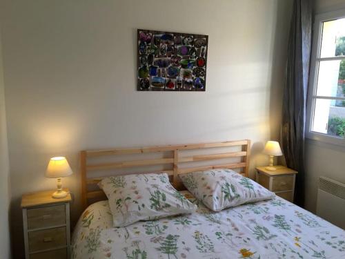 een slaapkamer met een bed met 2 lampen en een foto aan de muur bij villa des chênes in Flayosc