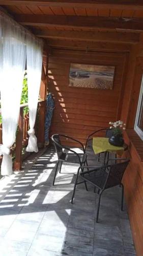2 sillas y una mesa en el porche de una cabaña en Domki na wynajem w Kątach Rybackich, en Kąty Rybackie