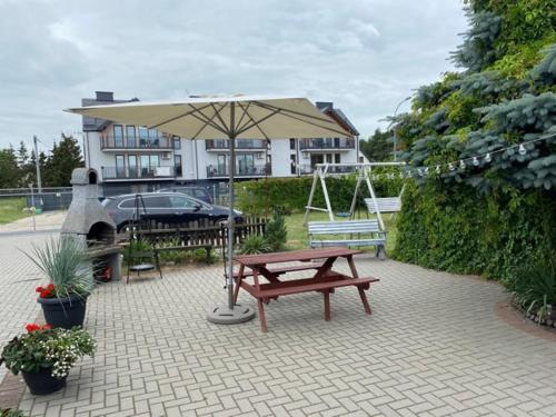 a picnic table and an umbrella in front of a house at Domki na wynajem w Kątach Rybackich in Kąty Rybackie