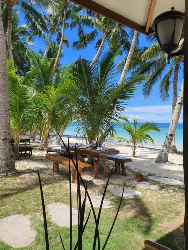 a picnic table on the beach with palm trees at Charisma Beach Resort in Siquijor