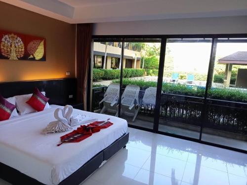 a bedroom with a bed and a balcony with a pool at Naiyang Beach Hotel SHA Plus in Nai Yang Beach