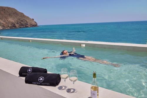 a woman laying in a swimming pool next to the ocean at Ancón Suites in Carboneras