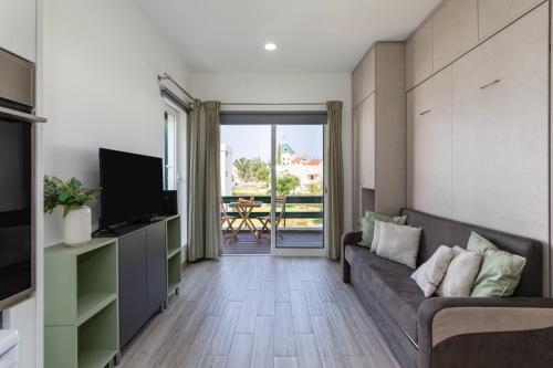 a living room with a couch and a television at Centralgarve - Elegant and Cosy Studio in the Heart of Vilamoura - Aldeia do Mar T0 in Vilamoura