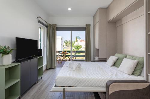 a bedroom with a bed and a tv and a balcony at Centralgarve - Elegant and Cosy Studio in the Heart of Vilamoura - Aldeia do Mar T0 in Vilamoura