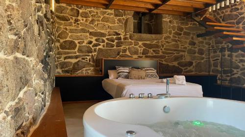 a bath tub in a room with a bed at Apartamentos Villa Maceira in Covelo