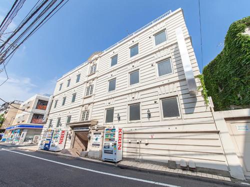 ein weißes Gebäude an der Straßenseite in der Unterkunft HOTEL LiVEMAX BUDGET Nippori in Tokio
